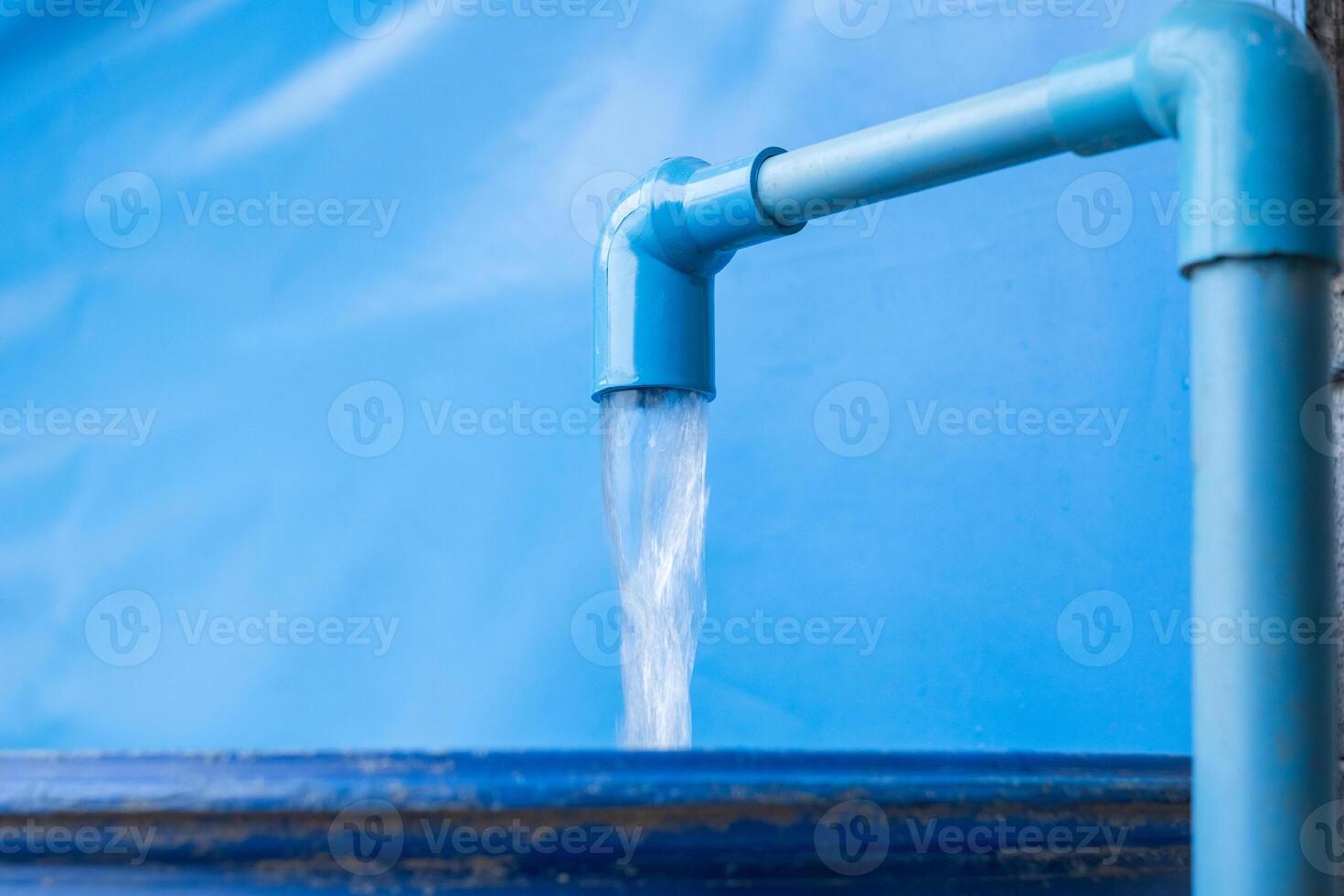 Blue pvc pipe with flowing water in bucket photo