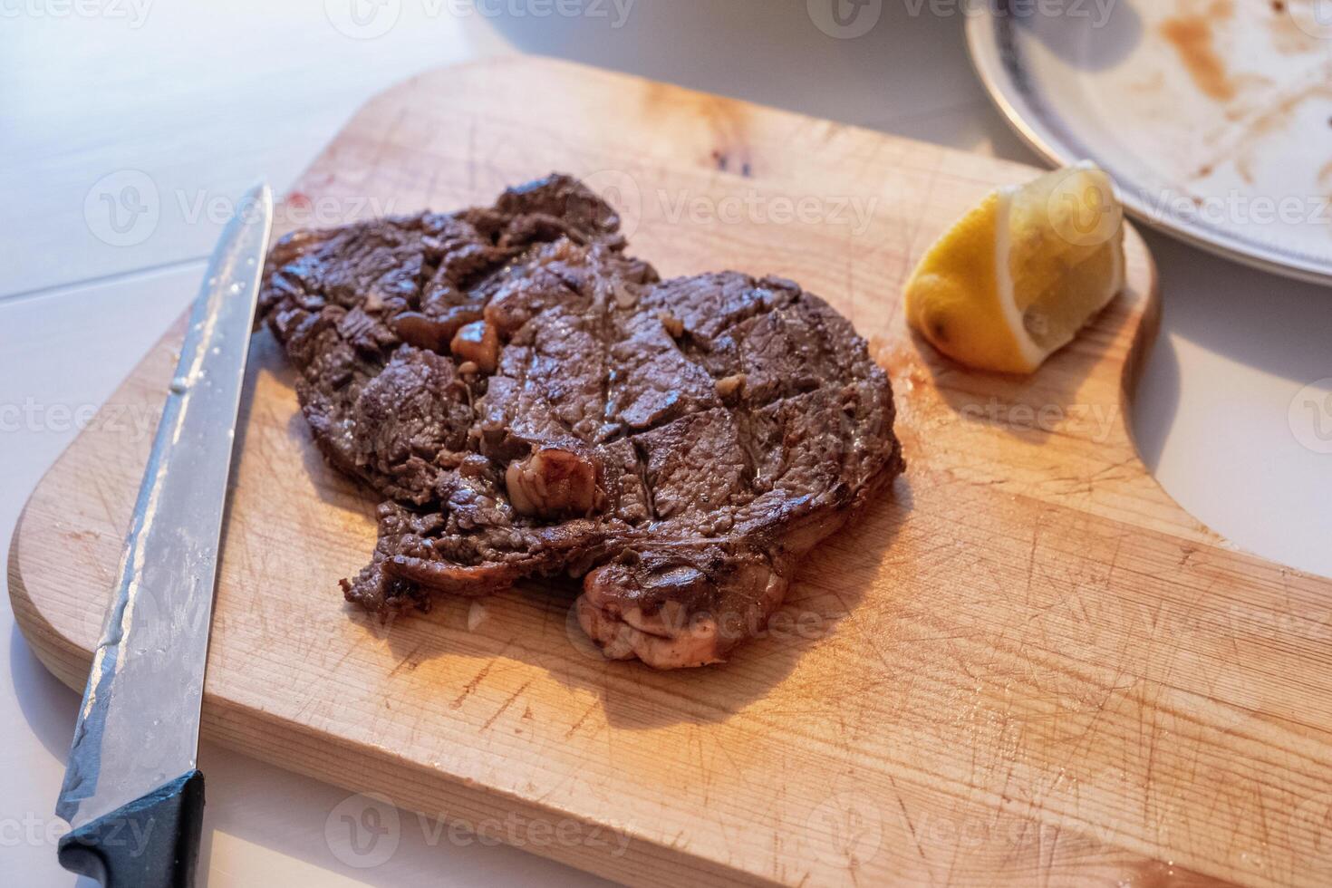 Medium rare Beef grilled with lemon slice on wood chopping block photo