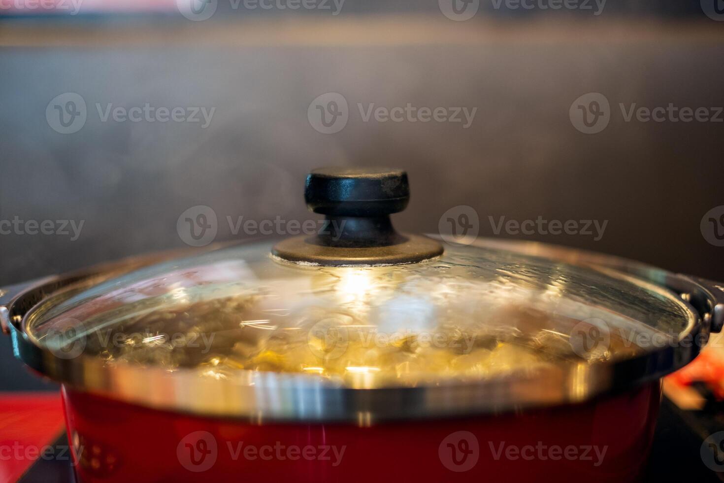 Boiling soup in red pot with smoke on table photo