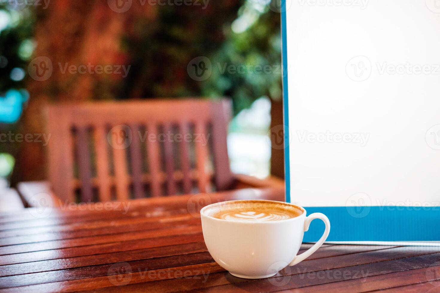 White coffee latte cup with blank signboard on wooden desk photo