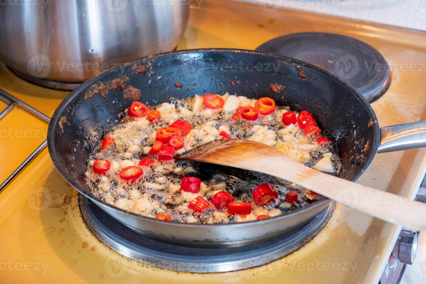 Wooden flipper frying chili with garlic on vegetable oil photo
