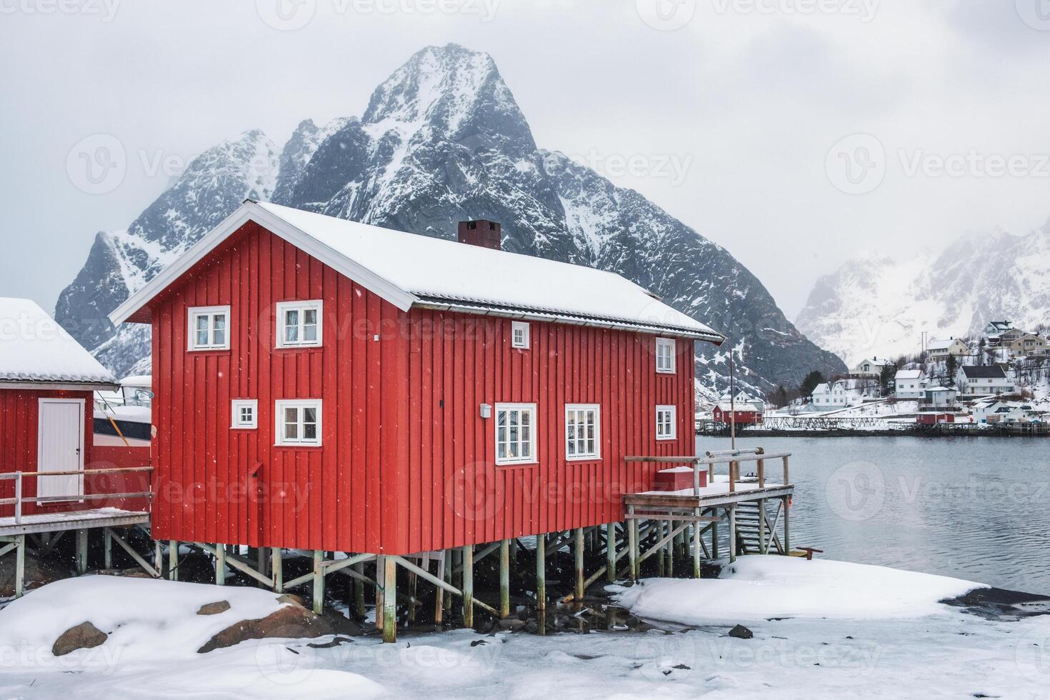 Snowfall on red house in valley on coastline at lofoten photo