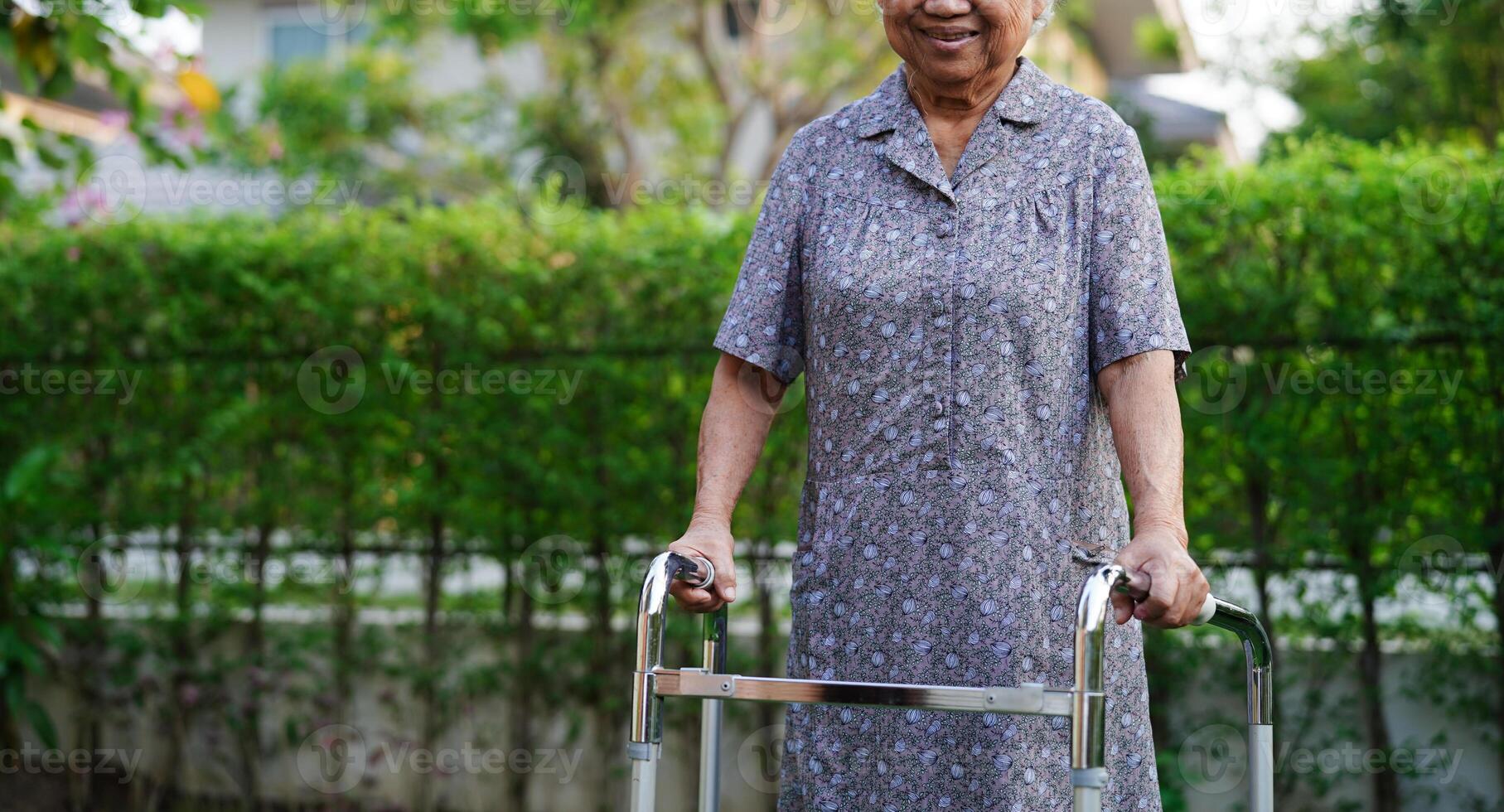 Asian elderly woman disability patient walk with walker in park, medical concept. photo