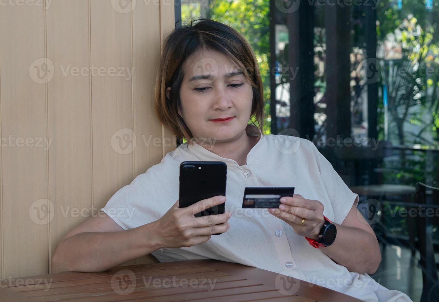 mujer sentado en silla a al aire libre el café participación crédito tarjetas y utilizando teléfono inteligente a compras en línea pagos, internet bancario aplicaciones y comercio electrónico foto