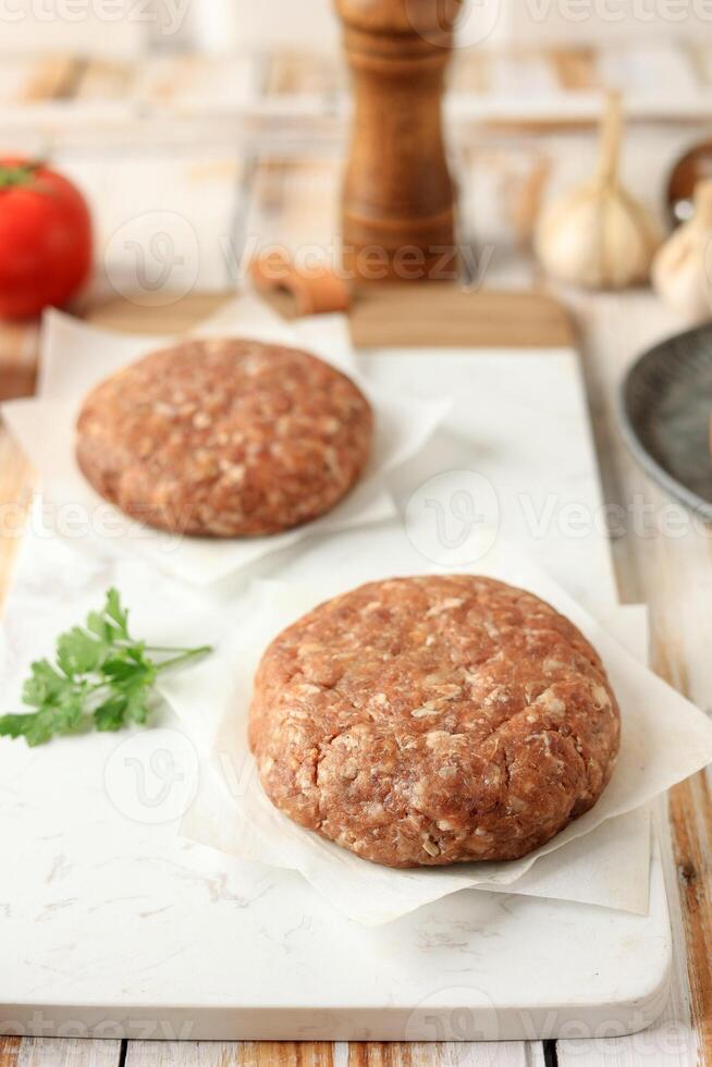 Raw Meat Burger Bun on Wooden Table photo