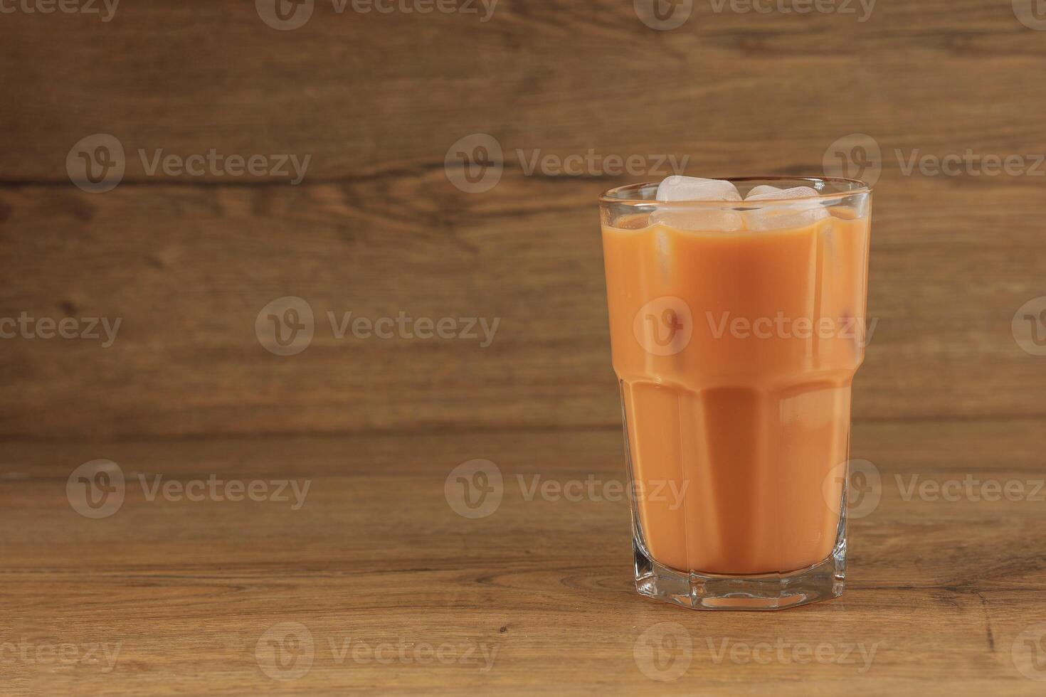 A Glass of Ice Thai Milk Tea on Wooden Table photo