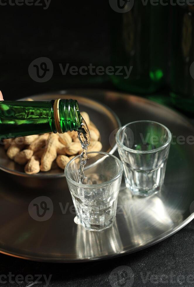 Pouring Soju or Mineral Water to Small Glass Cup. photo