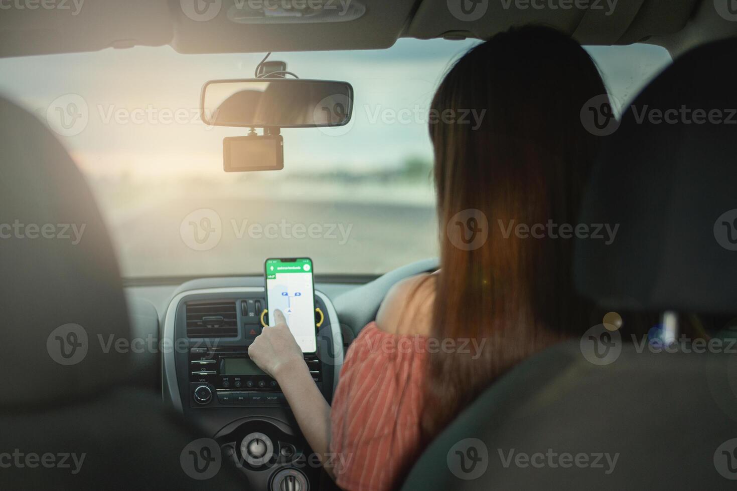 Driver using GPS navigation in mobile phone while driving car at sunset photo