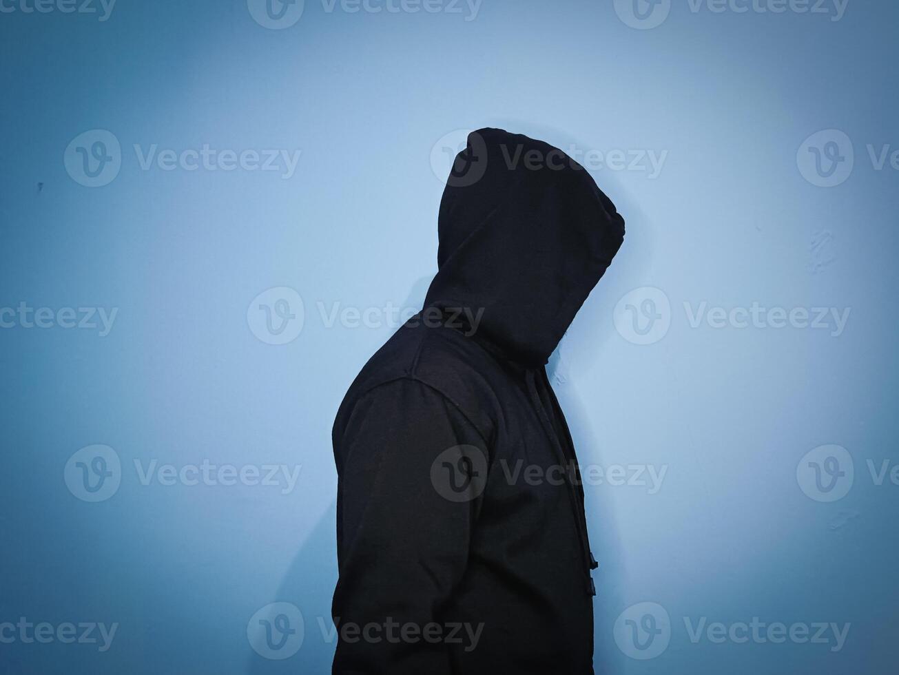 un hombre en un negro chaqueta poses con su capucha apagado foto