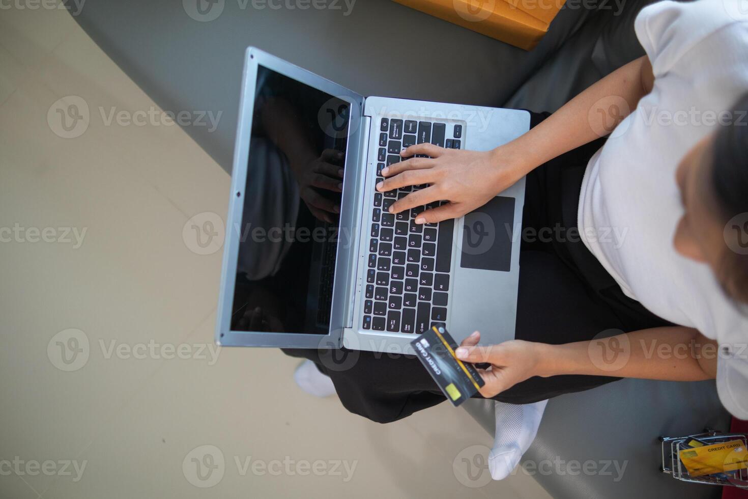 woman sitting in her room is happily shopping for gifts online with her credit card as she prepares for Christmas. woman uses laptop to access an online shopping website and pay with her credit card. photo