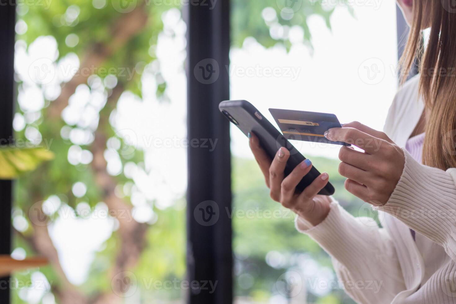 Young woman is shopping online through mobile application by paying with her credit card Convenience of paying through shopping online. Concept of online shopping and spending through credit card. photo
