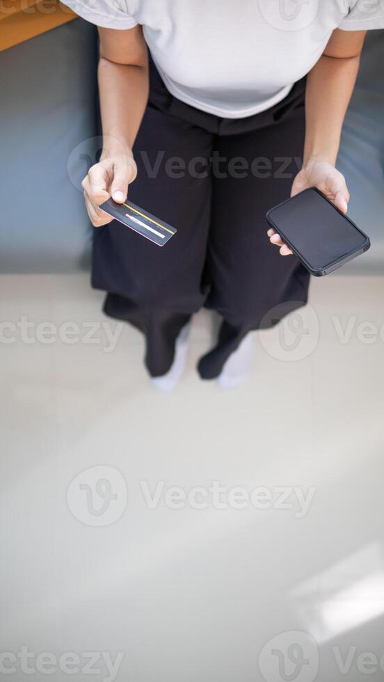 Young woman is shopping online through mobile application by paying with her credit card Convenience of paying through shopping online. Concept of online shopping and spending through credit card. photo