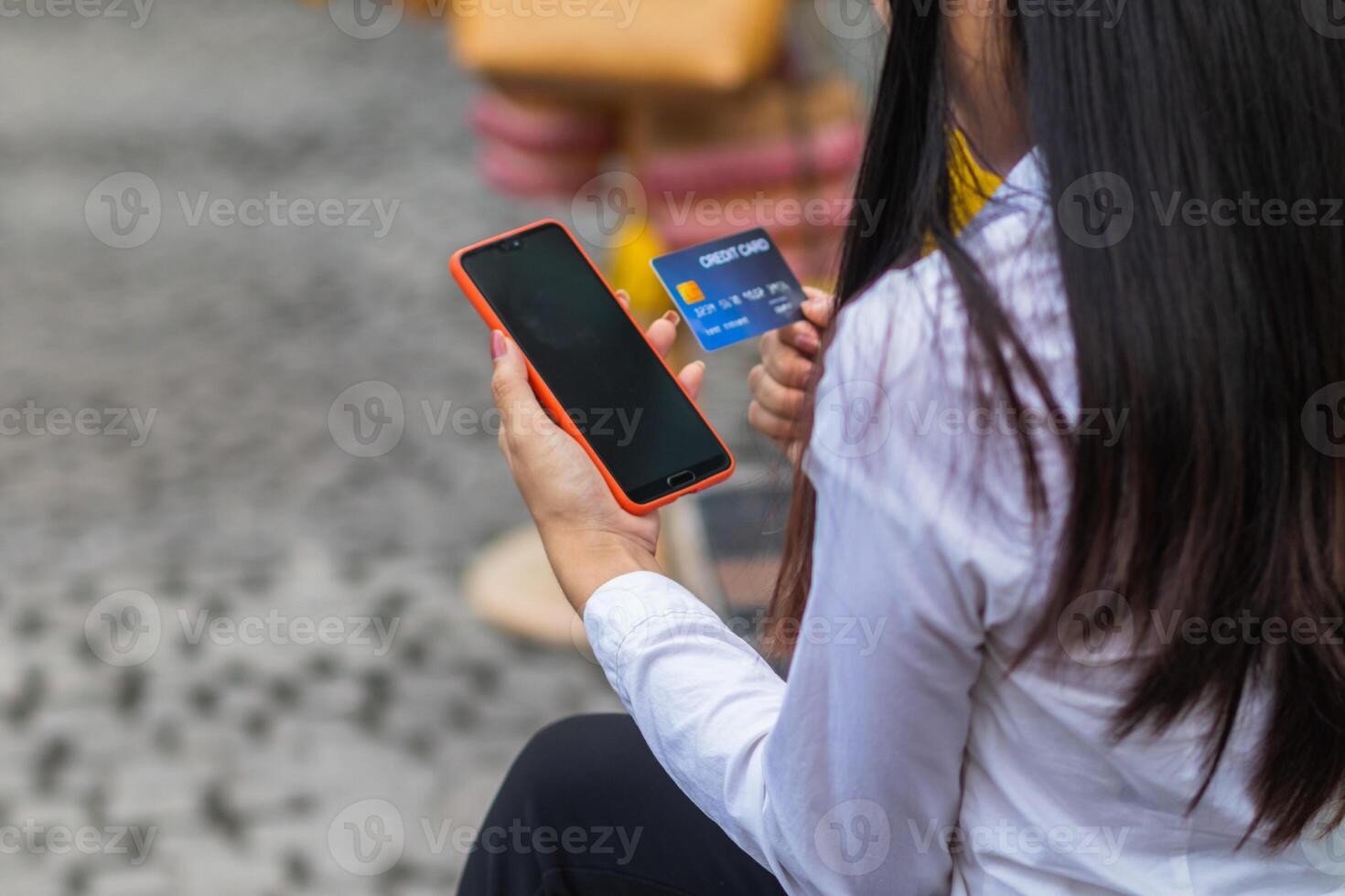 Young woman is shopping online through mobile application by paying with her credit card Convenience of paying through shopping online. Concept of online shopping and spending through credit card. photo