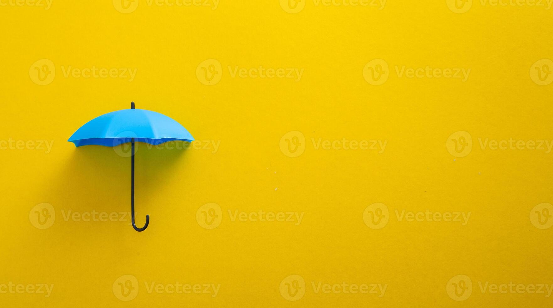 Blue toy umbrella on yellow background. photo