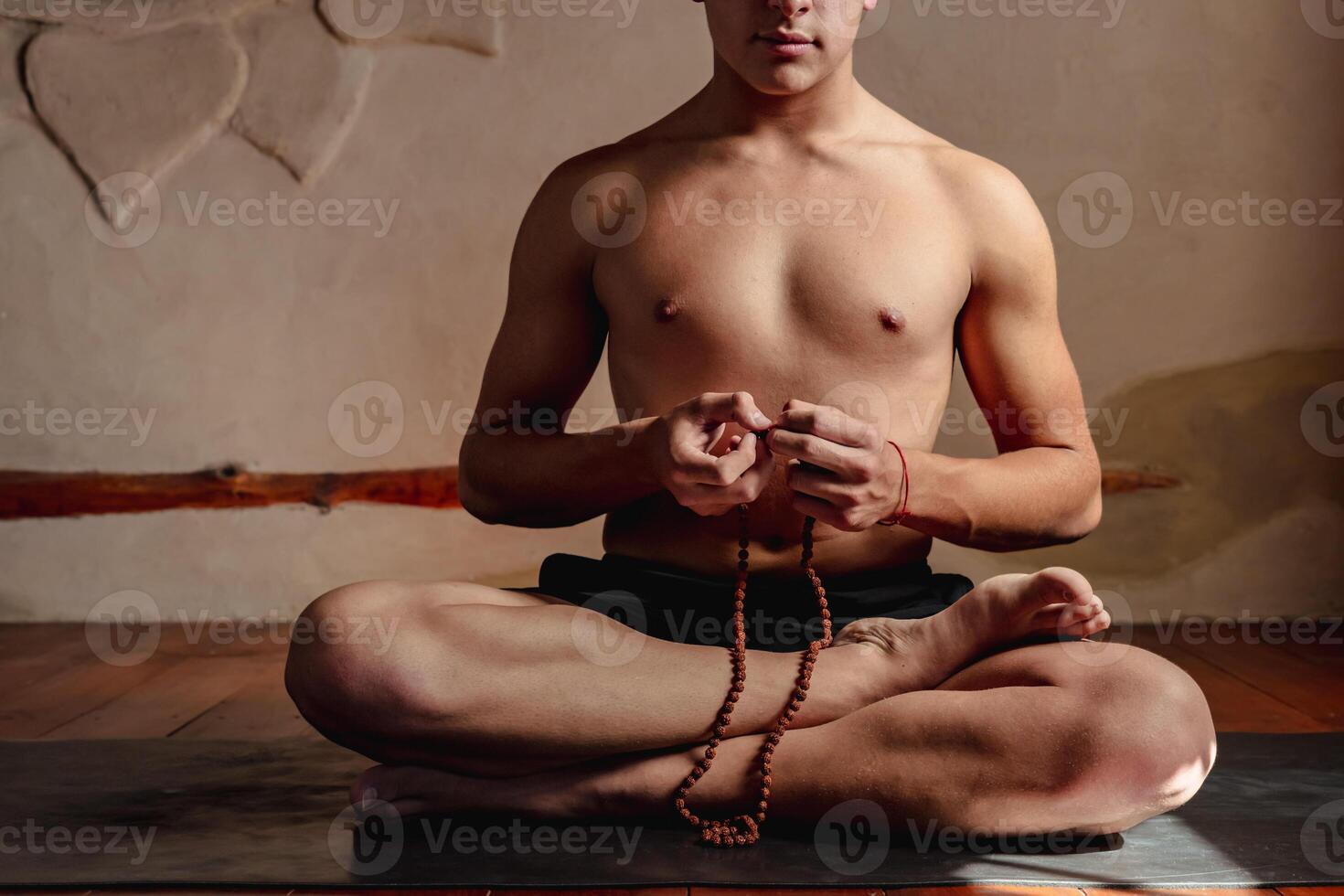 joven irreconocible hombre meditando con un Rudraksha mala en su manos. foto