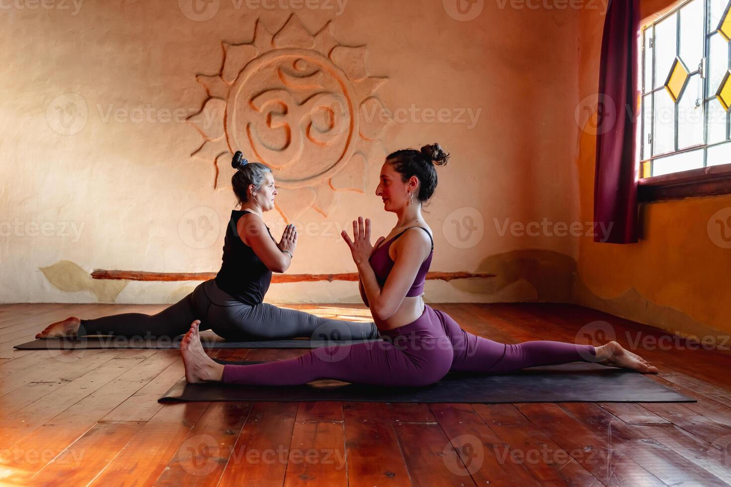 Two women of different ages practicing advanced yoga on a mat. photo