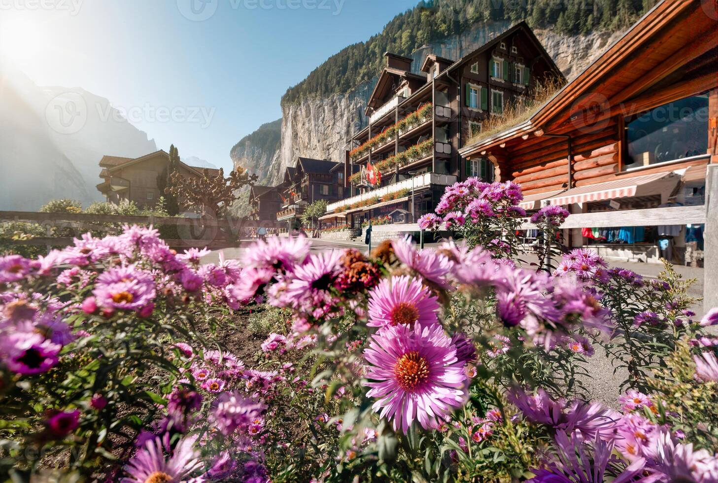 Rustic village with flower blooming, wooden hotel and waterfall flowing from the mountain in Lauterbrunnen, Switzerland photo