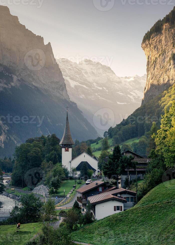 View of Lauterbrunnen valley with rustic village, famous church and Staubbach falls during end of summer at Switzerland photo