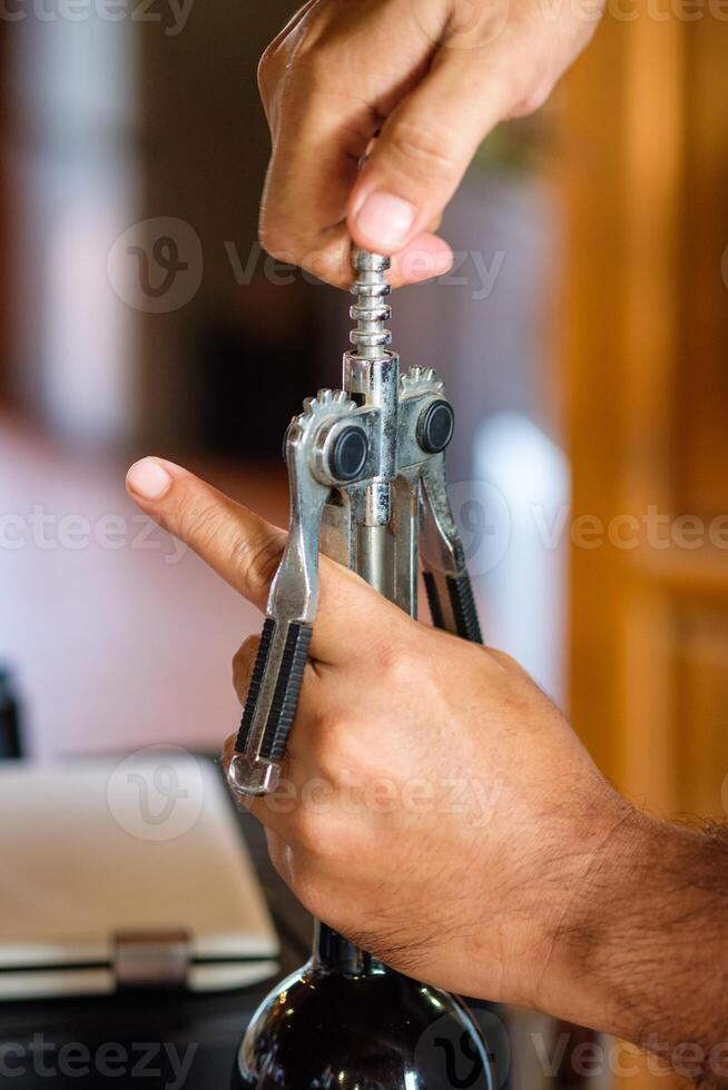 Hand waiter opening crok wine with lever opener photo