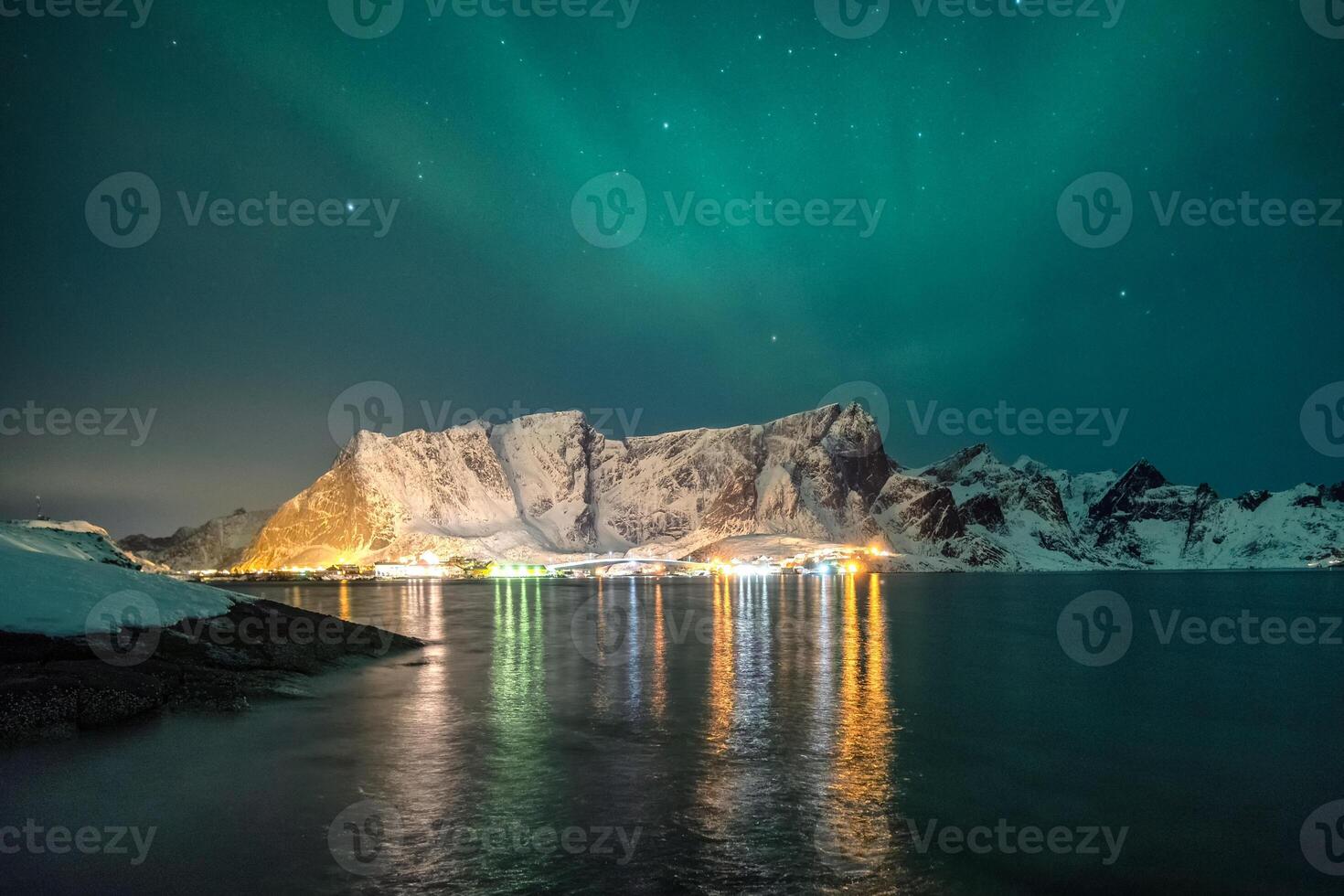 Nevado montaña rango con Aurora borealis y brillante ciudad foto