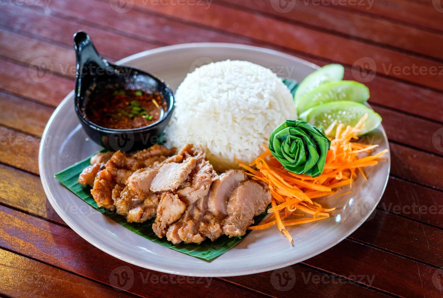 Grilled pork sliced with spicy sauce and white rice on plate photo