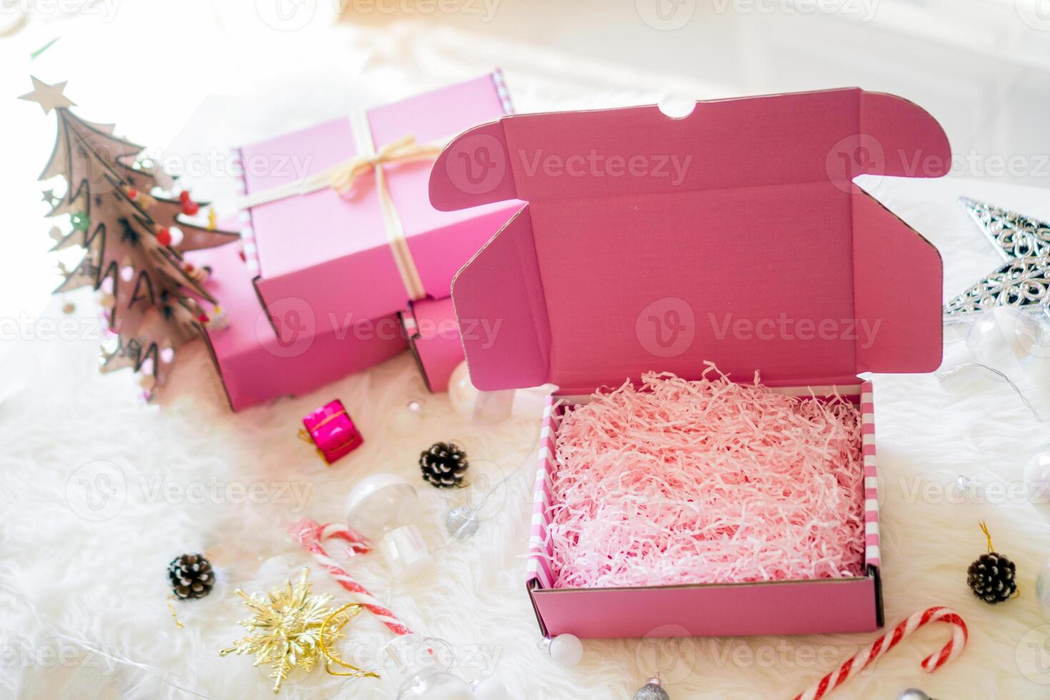 Pink gift boxes open bow ribbon with bright lamp, candy and star on white carpet photo