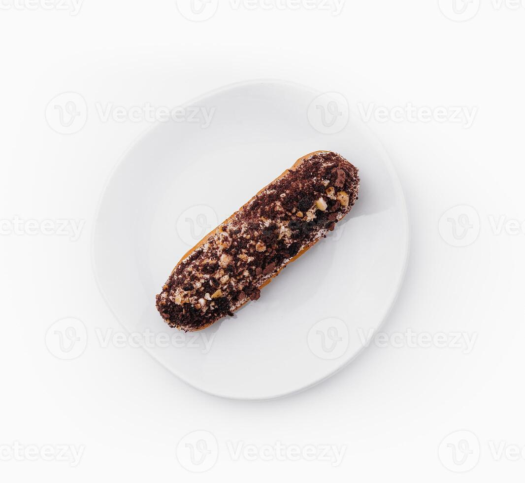 eclair with chocolate and nuts on a white plate photo