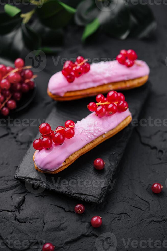 eclair with red currants on black stone photo