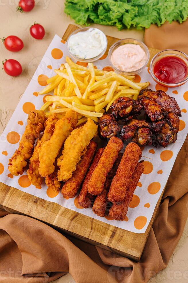 fried nuggets and spicy chicken legs, wings and french fries potatoes photo