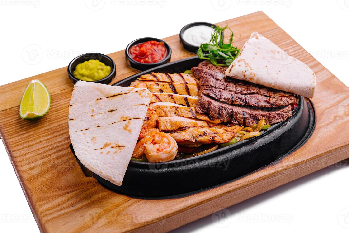 Beef chicken and shrimp fajitas on a iron cast sizzling plate photo