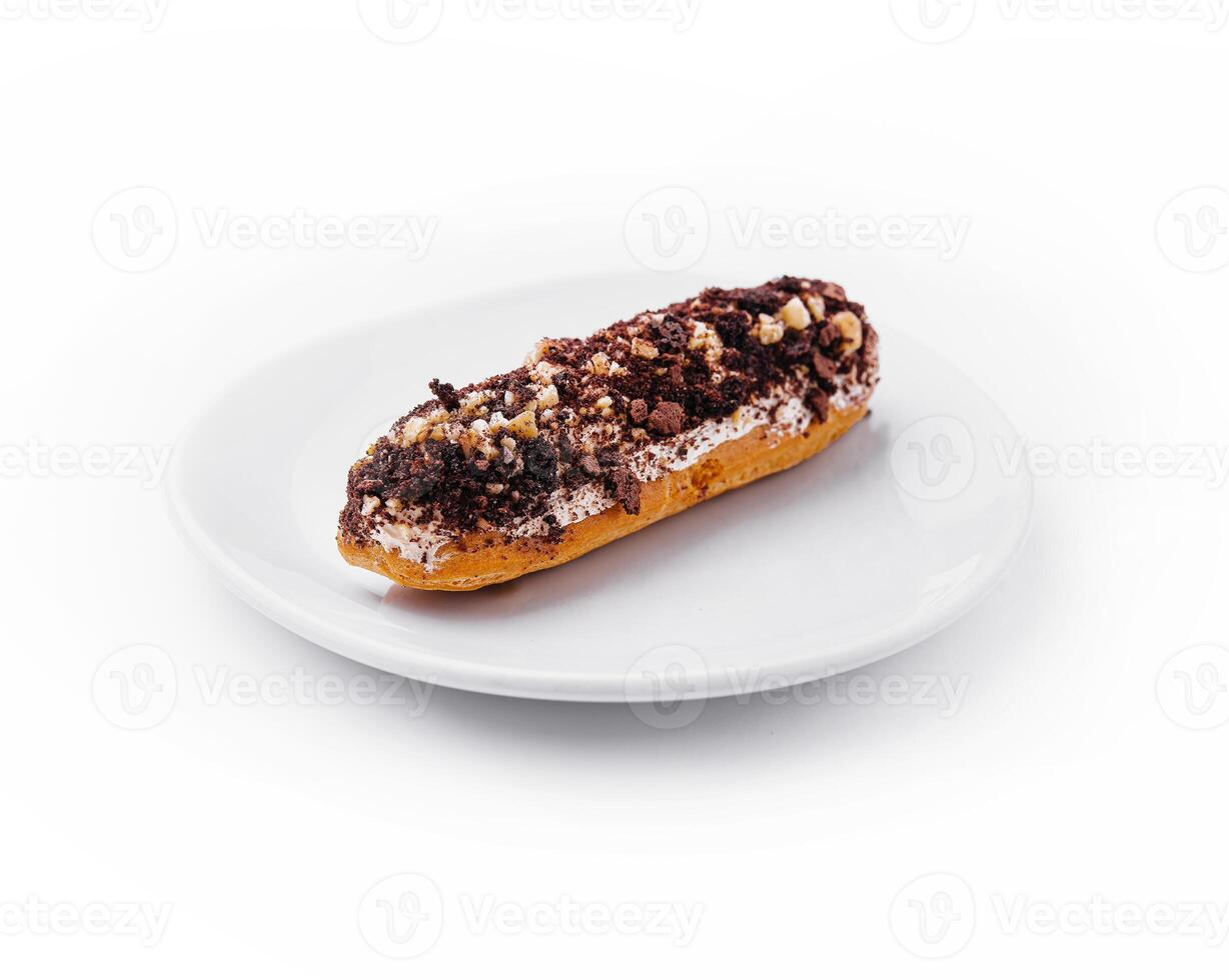 eclair with chocolate and nuts on a white plate photo