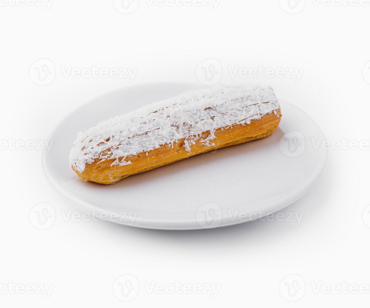 eclair in white glaze and coconut flakes photo