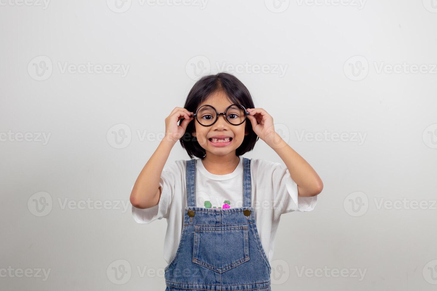 cute little preschooler girl isolated on grey studio background wear glasses look at camera, small child try spectacles at opticians, kid eyesight correction treatment concept photo