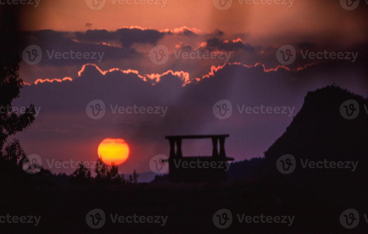 the sun sets behind a mountain range in the background photo