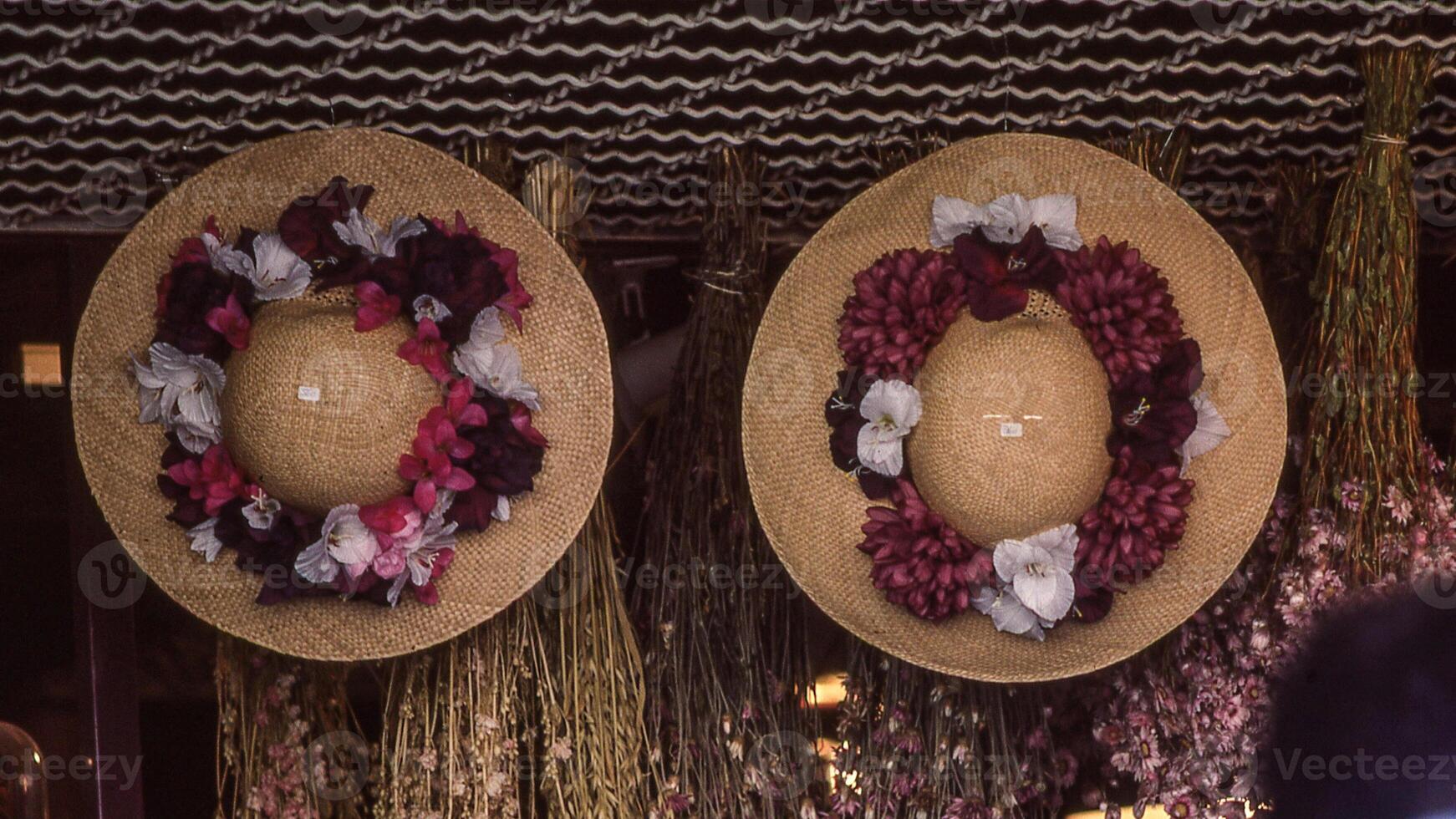 two hats with flowers on them are hanging on a wall photo