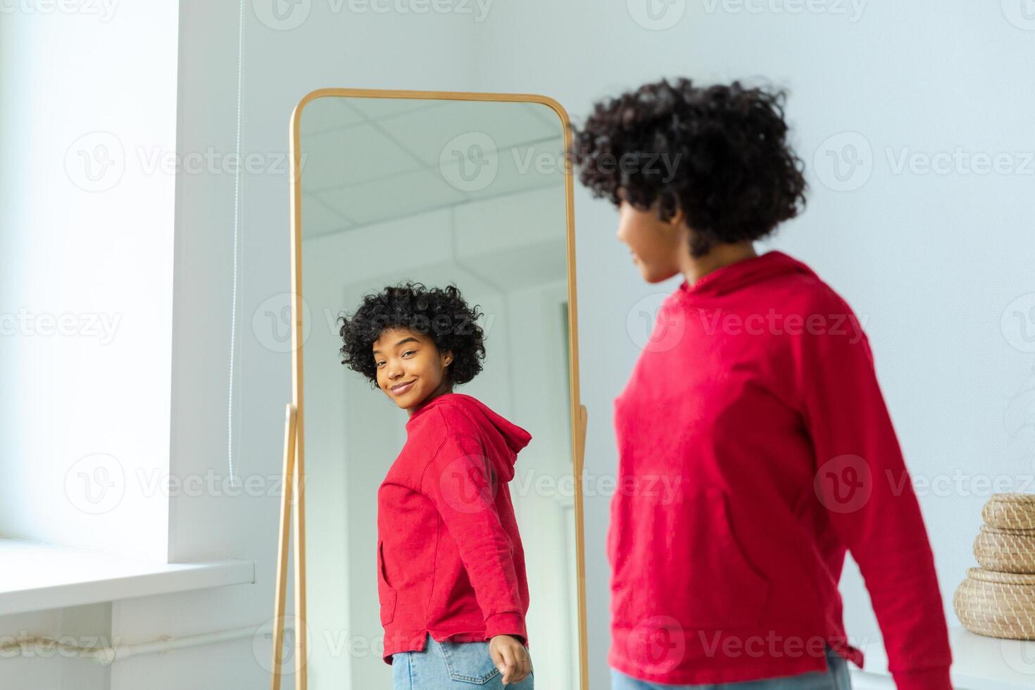 Love yourself. Beautiful young smiling african american woman dancing enjoying her mirror reflection. Black lady looking at mirror looking confident and happy. Self love concept photo