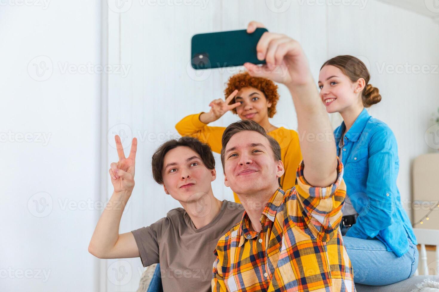 Cheers Funky mood. Happy group of friends make selfie. Man taking photo of friends at party. Group of multiracial young people taking photo on phone. Young people enjoy their company smile have fun