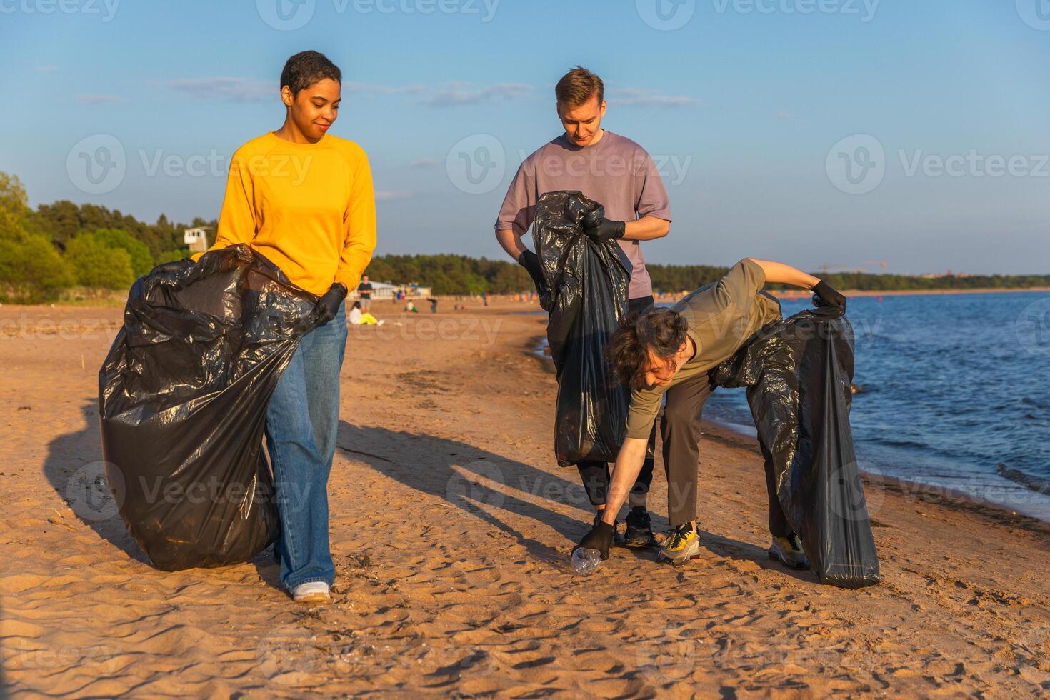 Earth day. Volunteers activists team collects garbage cleaning of beach coastal zone. Woman mans with trash in garbage bag on ocean shore. Environmental conservation coastal zone cleaning photo