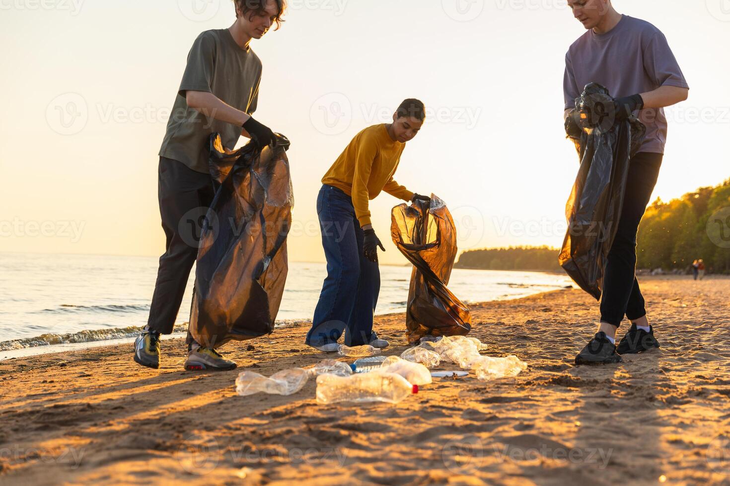 tierra día. voluntarios activistas recoge basura limpieza de playa costero zona. mujer y mans pone el plastico basura en basura bolso en Oceano costa. ambiental conservación costero zona limpieza foto
