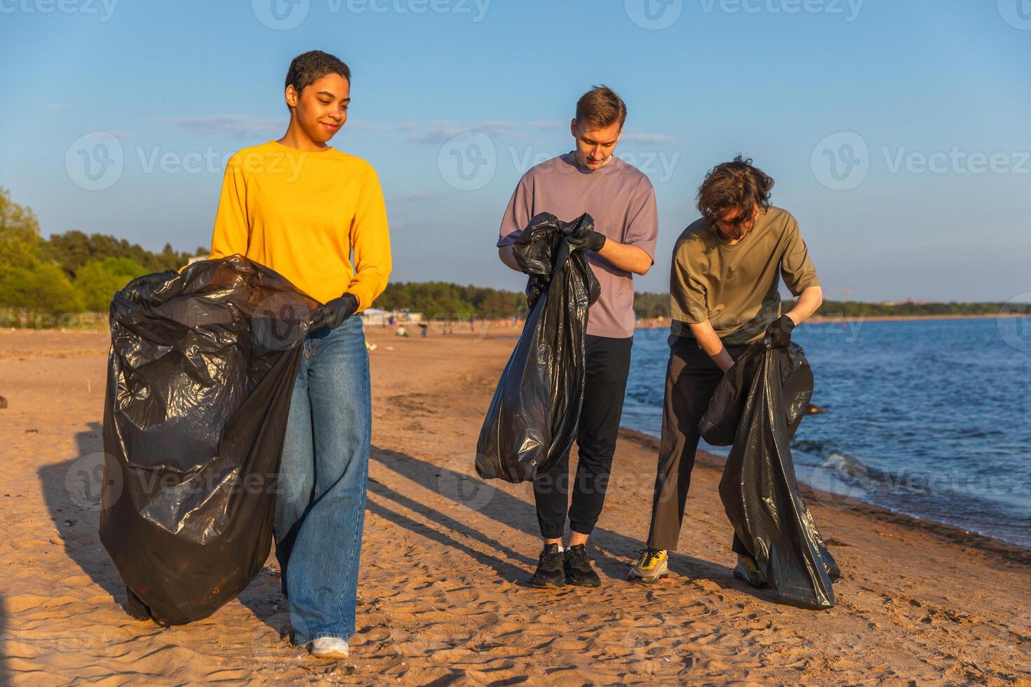 tierra día. voluntarios activistas equipo recoge basura limpieza de playa costero zona. mujer mans con basura en basura bolso en Oceano costa. ambiental conservación costero zona limpieza foto