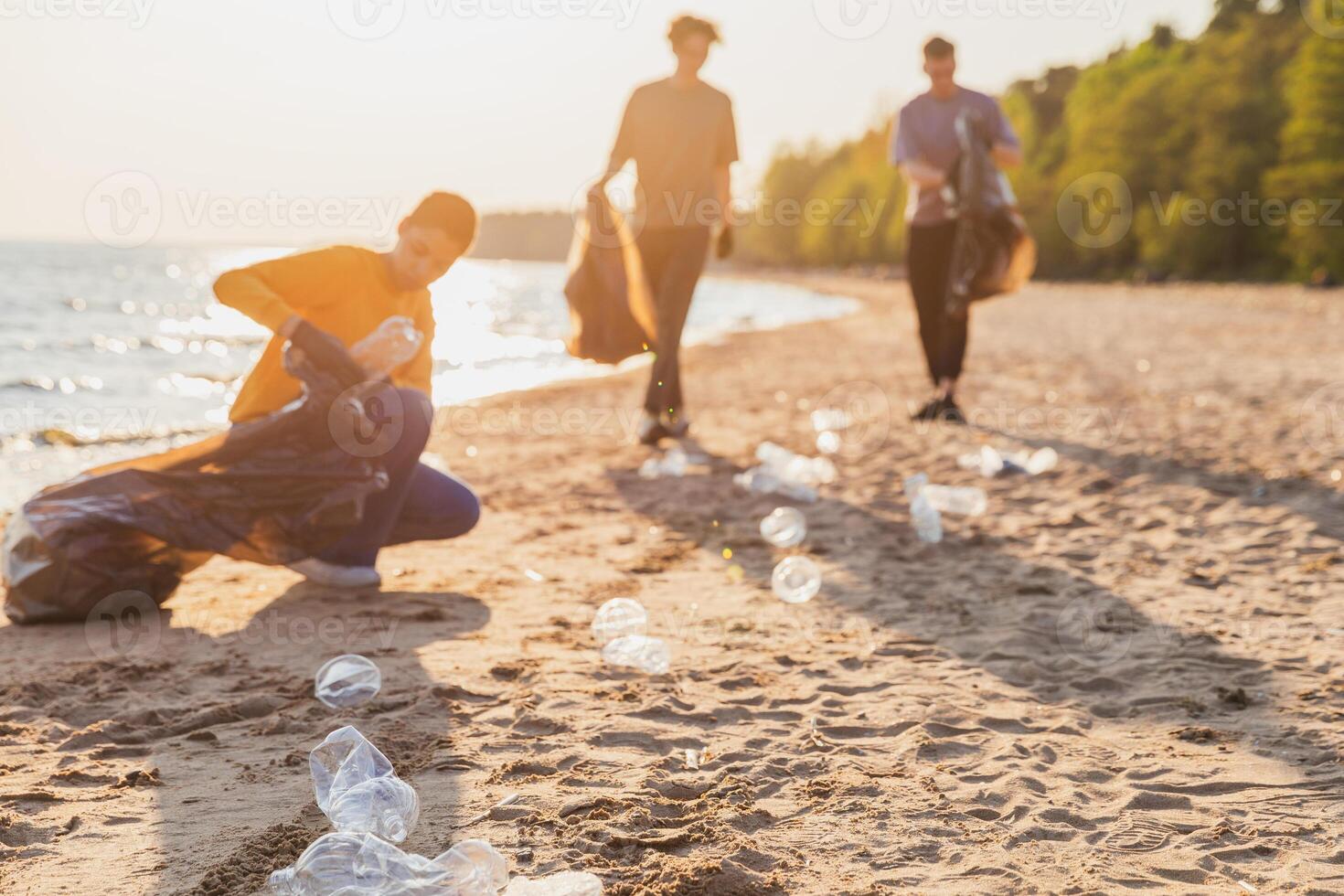 Earth day. Volunteers activists team collects garbage cleaning of beach coastal zone. Woman mans puts plastic trash in garbage bag on ocean shore. Environmental conservation coastal zone cleaning photo