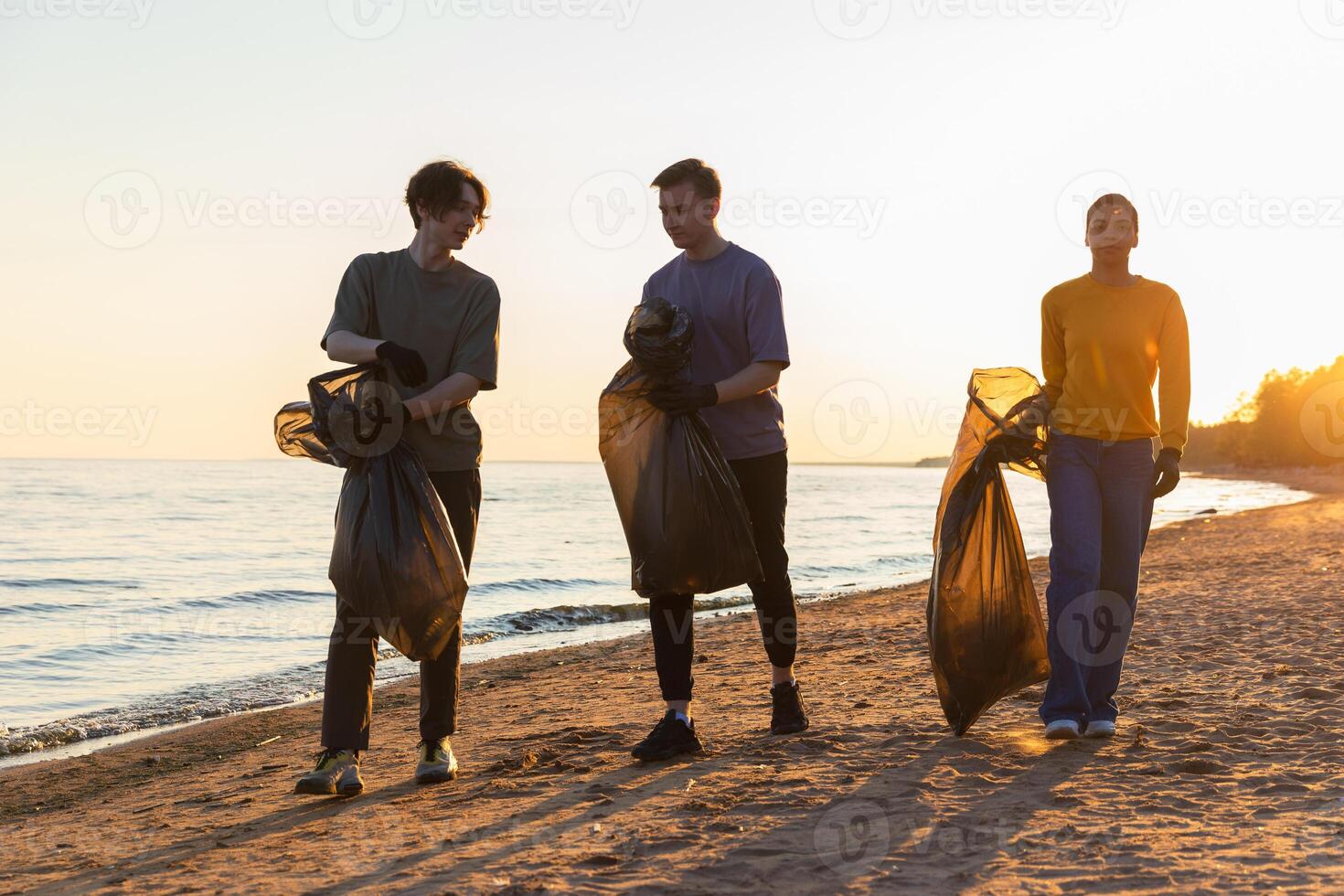 Earth day. Volunteers activists team collects garbage cleaning of beach coastal zone. Woman mans with trash in garbage bag on ocean shore. Environmental conservation coastal zone cleaning photo