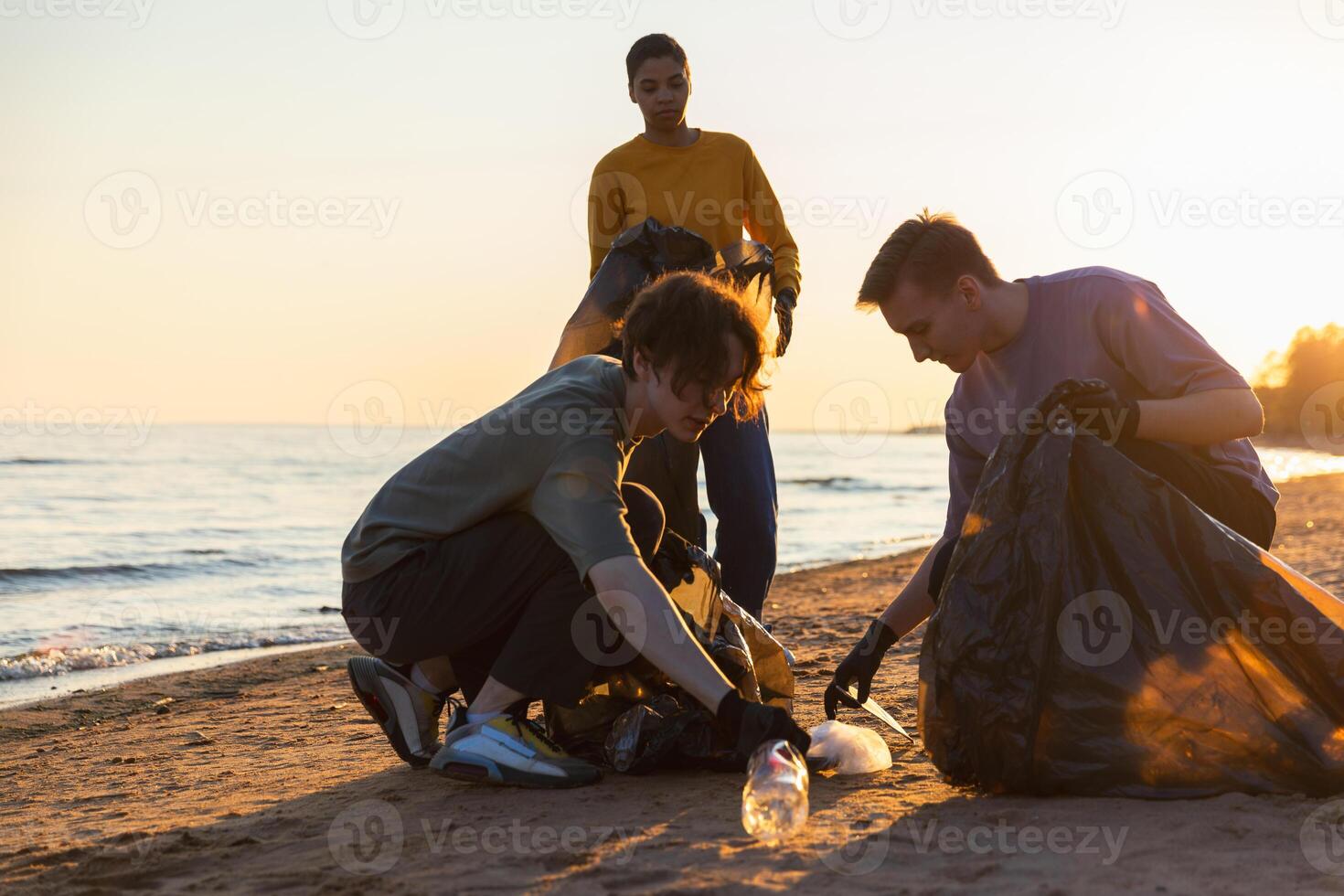 Earth day. Volunteers activists collects garbage cleaning of beach coastal zone. Woman and mans puts plastic trash in garbage bag on ocean shore. Environmental conservation coastal zone cleaning photo