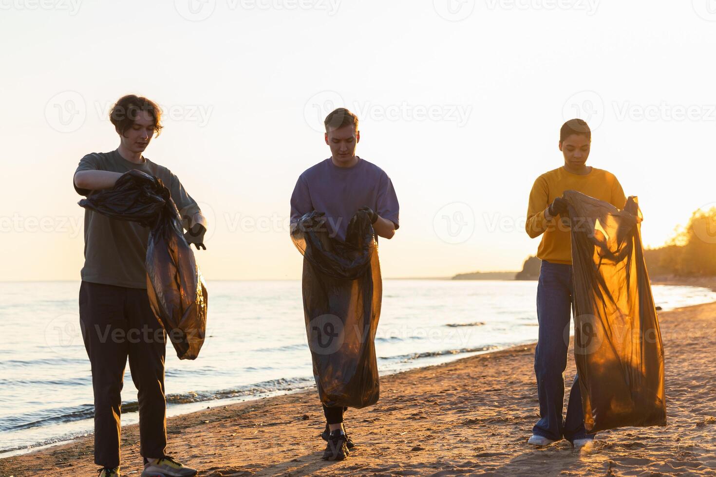 Earth day. Volunteers activists team collects garbage cleaning of beach coastal zone. Woman mans with trash in garbage bag on ocean shore. Environmental conservation coastal zone cleaning photo