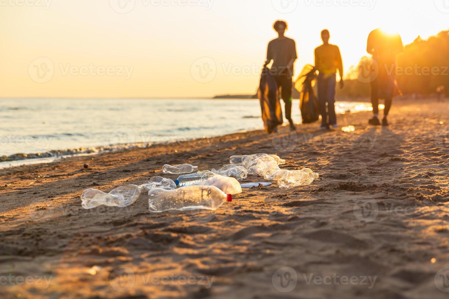 Earth day. Volunteers activists team collects garbage cleaning of beach coastal zone. Woman mans with trash in garbage bag on ocean shore. Environmental conservation coastal zone cleaning photo