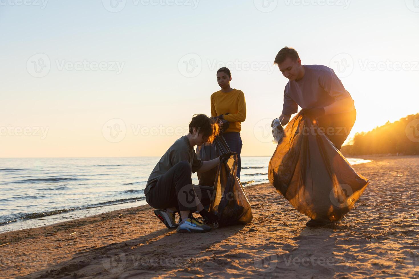 Earth day. Volunteers activists collects garbage cleaning of beach coastal zone. Woman and mans puts plastic trash in garbage bag on ocean shore. Environmental conservation coastal zone cleaning photo