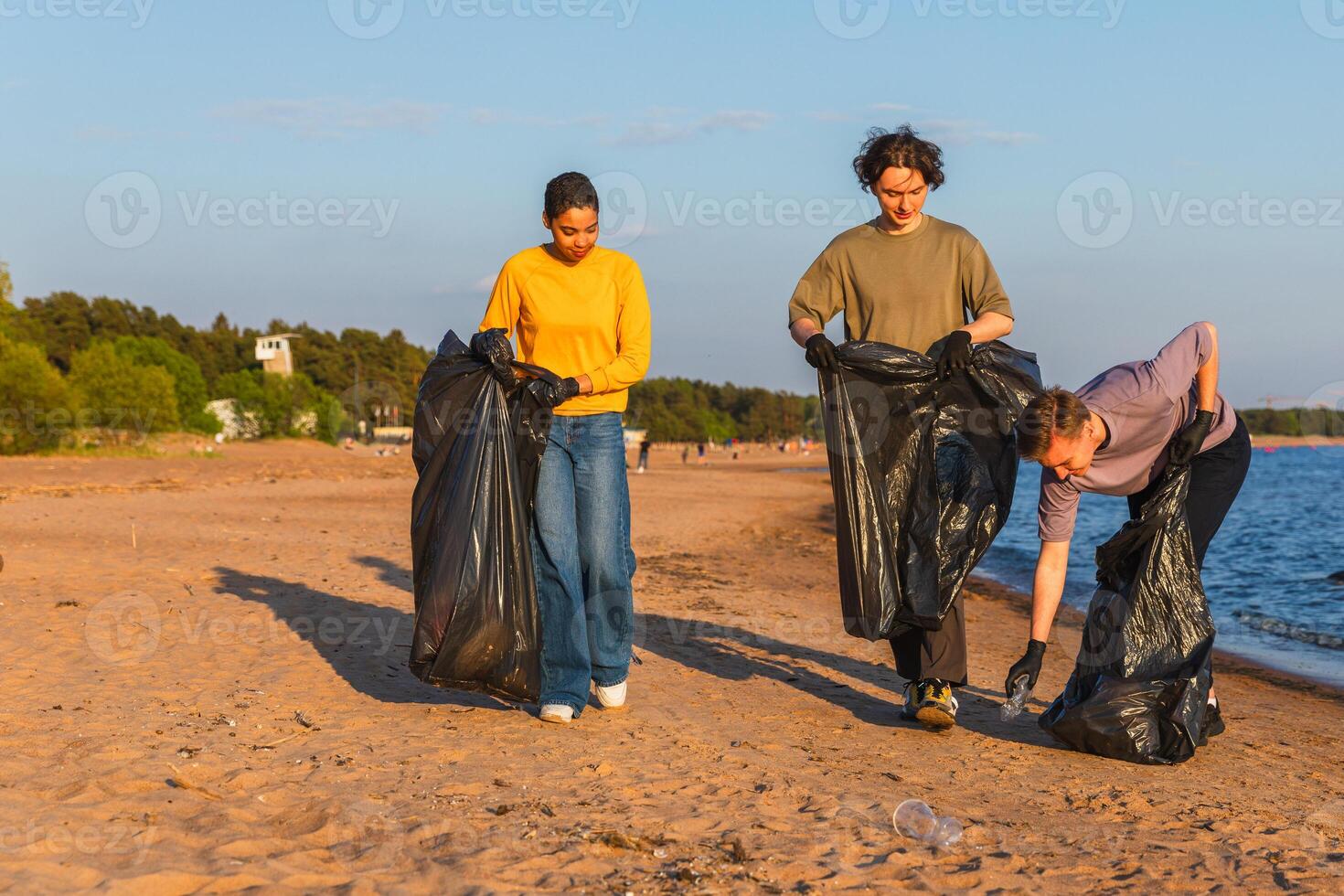 Earth day. Volunteers activists team collects garbage cleaning of beach coastal zone. Woman mans with trash in garbage bag on ocean shore. Environmental conservation coastal zone cleaning photo