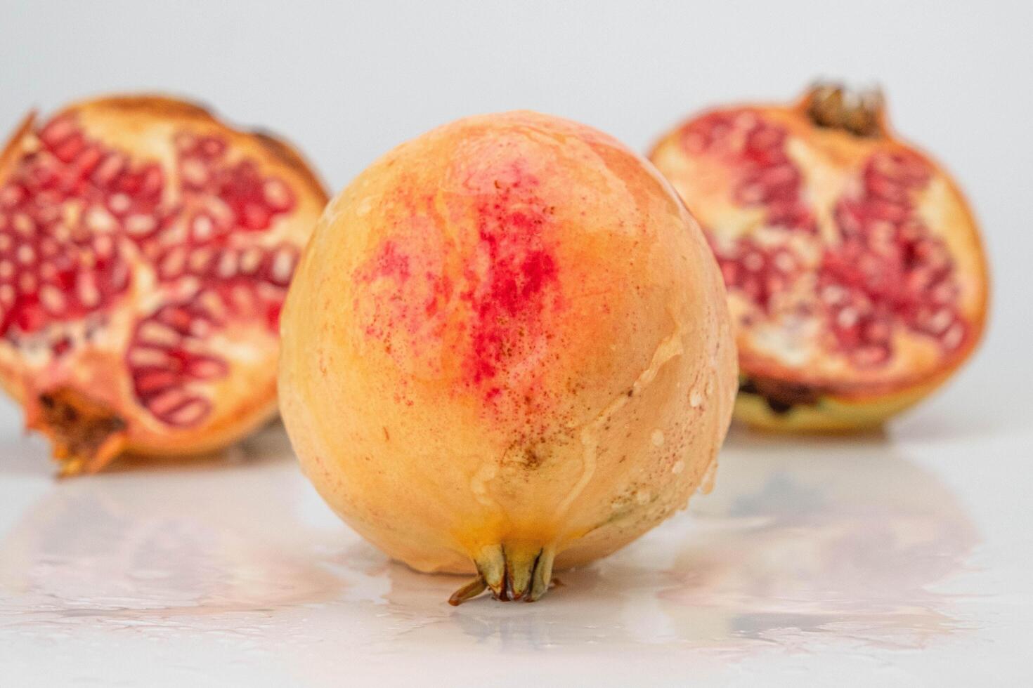 Fresco granada con jugo chapoteo y granada cortar en medio como antecedentes. maduro Fruta es un sano alimento. foto