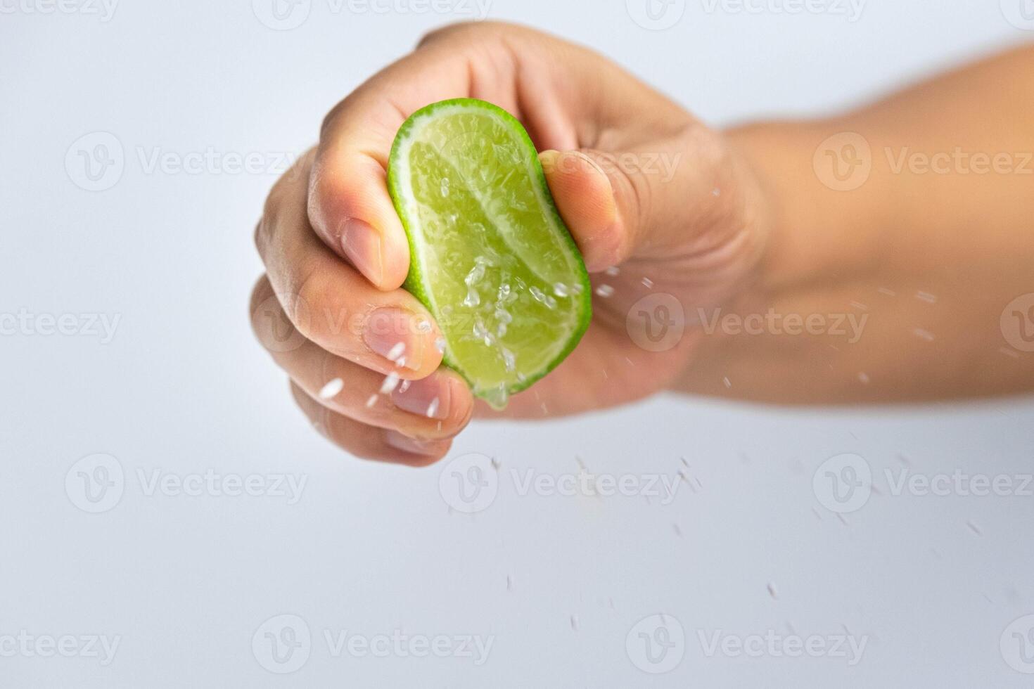 Female hand squeezing half fresh lemon isolated on white background. Squeezing fresh lemon close up. Hight Vitamin C Natural photo