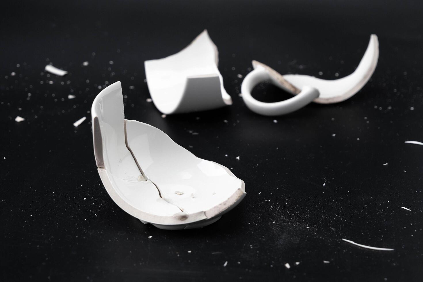 Large white mug with cracks. White cup for tea or soup with cracks isolated on dark background. Broken ceramic cup close up. symbol of divorce or loss photo